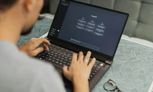 Person typing on a laptop showing ChatGPT