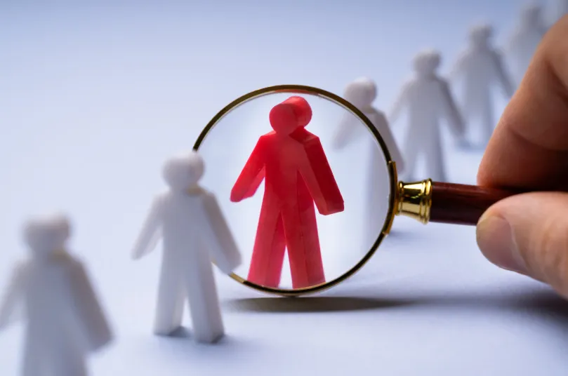 Magnifying glass highlighting one figure among many
